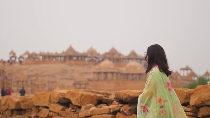 Portrait of young woman wearing Indian salwar suit looking at architecture of Bada Bagh in Jaisalmer, Rajasthan, India. Tourist exploring heritage, culture of India. Travel and Holidays background.