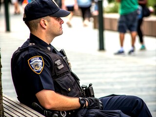 Close-up of a policeman's torso seated and attentively listening, showcasing detailed uniform, badge, and police gear, highlighting the professionalism and dedication in law enforcement.