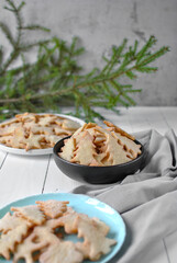 Three different plates on a white wooden background, next to a drapery of gray fabric, with a spruce branch in the background.