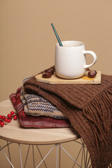 Cozy winter lifestyle concept. Cup of hot drink with warm knitted clothes.	
