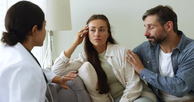 Stressed shocked young woman learning serious hard diagnosis from practitioner. Latin couple consulting doctor, getting bad news about health problems, infertility, difficult therapy need