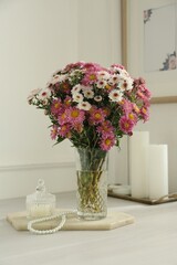 Beautiful flowers in glass vase and decor on white wooden table at home