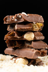 Pieces of milk nut chocolate on a black background.