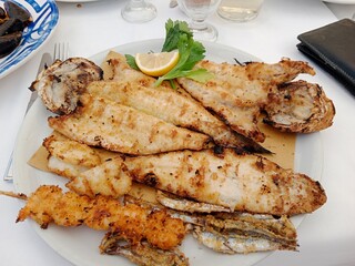 Grilled fish, with a piece of monkfish, a piece of sea bass, a skewer of prawns and a skewer of...