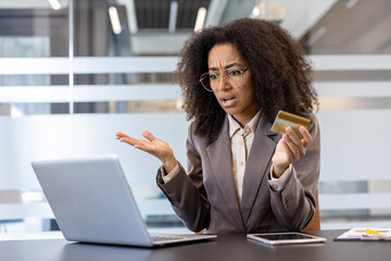 Credit card problems. African american young upset woman sitting in the office at the desk and...