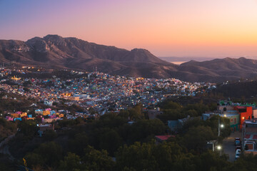 The illuminated cityscape of Guanajuato, Mexico glows vibrantly at blue hour, nestled among hills...