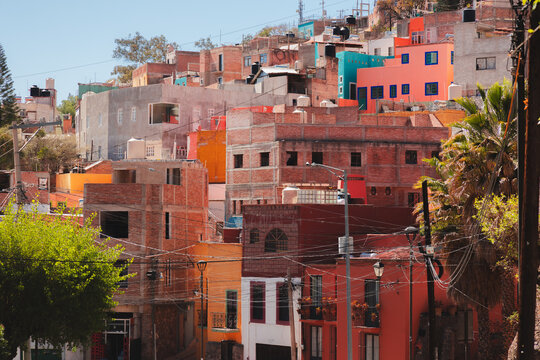 Vibrant multicolored buildings in a hillside neighborhood of Guanajuato, Mexico, with eclectic architecture and rustic charm under the sunlight.