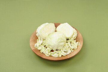 Green cabbage on a wooden plate, isolated against a green background, top view