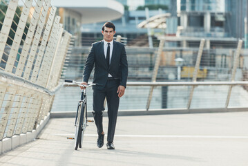 Handsome young business man with his modern bicycle.