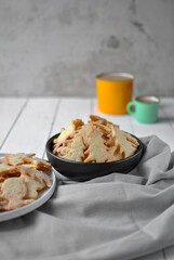 Homemade shortbread cookies in two plates, with two cups in the background. Vertical location.