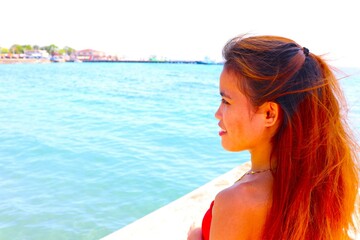 young woman in red dress looking out over ocean sea port