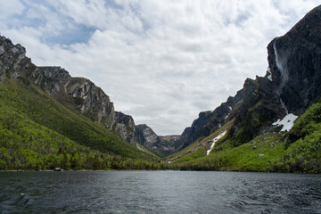 The eastern end of Western Brook Pond, where the fjord meets, features tranquil waters and towering cliffs, capturing the majestic beauty of Gros Morne National Park.