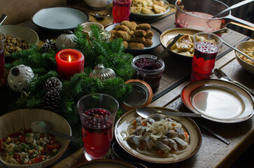 A festive Christmas Eve dinner table with many dishes, candle and Christmas decorations, traditional Lithuanian Christmas Eve dinner with 12 dishes