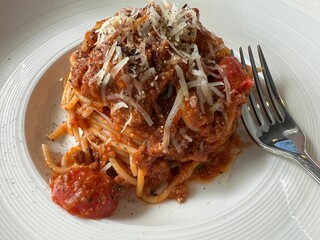 Closeup detailed shot of red sauce pasta topped with grated onions and black peppers powder