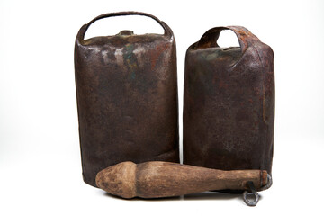 Isolated rusty iron cowbells with wooden clapper over white background