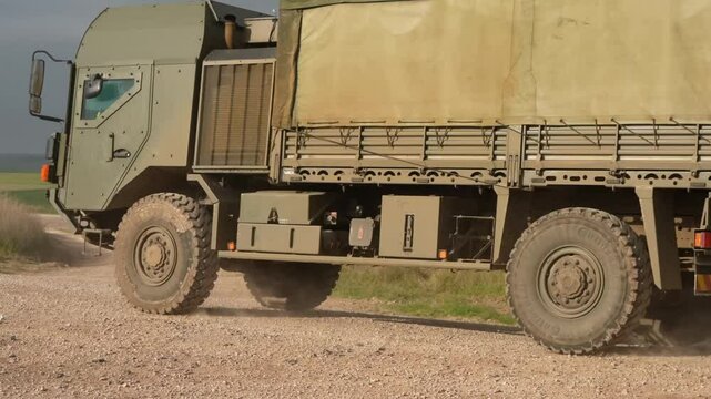 close-up of a convoy of British army MAN utility trucks moving along a dusty track