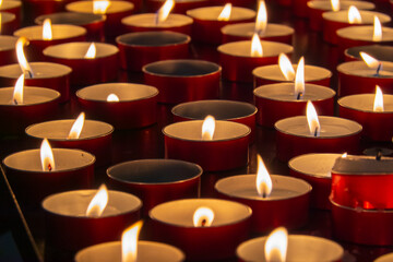 Rows of tea light candles in red holders glowing warmly, evoking peaceful, tranquil ambiance...