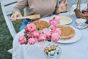 Woman preparing delicious waffles outdoors. Pink roses add a touch of romance to this idyllic summer scene. Perfect for blogs, magazines, and food websites.