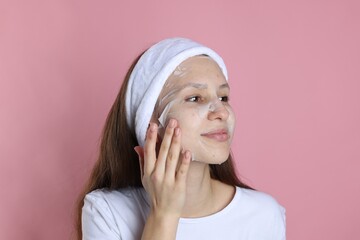 Teenage girl with sheet facial mask on pink background. Acne treatment