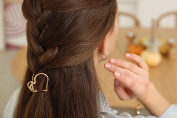 Teenage girl with stylish hair clip indoors, back view