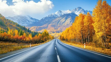 Scenic Autumn Road with Vibrant Orange and Yellow Trees Leading to Majestic Snow-Capped Mountains Under a Clear Blue Sky