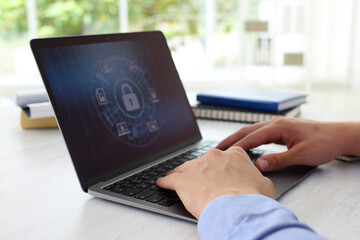 Cyber security. Man using laptop at table, closeup