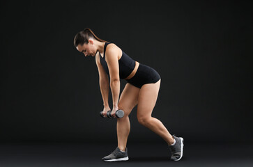 Obraz premium Woman exercising with dumbbells on black background