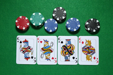 Playing cards and poker chips on green table, flat lay