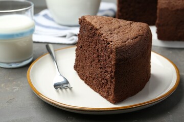 Piece of tasty chocolate sponge cake served on grey table, closeup