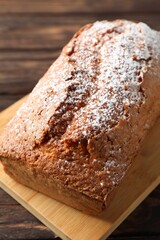 Tasty sponge cake with powdered sugar on wooden table, closeup