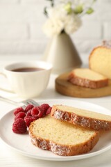 Freshly baked sponge cake and raspberries on white wooden table, closeup