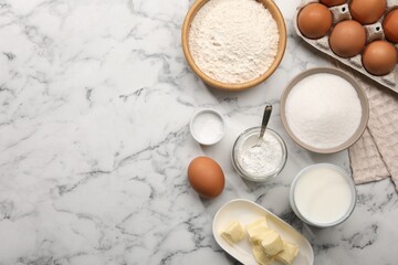 Baking powder and other products on white marble table, flat lay. Space for text