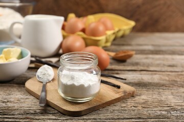 Baking powder in jar and other products on wooden table, closeup
