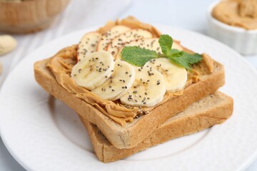 Tasty sandwich with peanut butter, apple, banana, chia seeds and mint on table, closeup