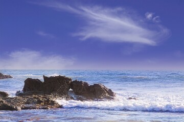 Wave crashing on a rock with a hole in it and some water comes through the hole. Laguna Beach, California.