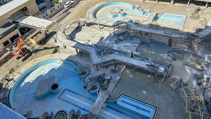 An aerial view of a construction site featuring swimming pools and recreational areas under development, suitable for real estate, architecture, or construction industries.