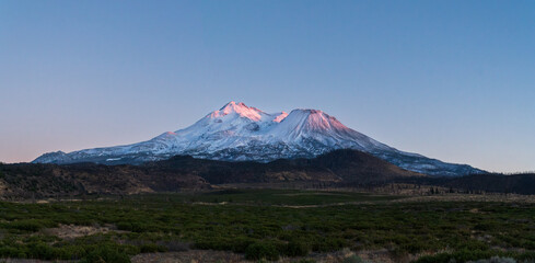 Fototapeta premium Last ray of sunlight on Mount Shasta volcano, California, USA, after an early season snowfall