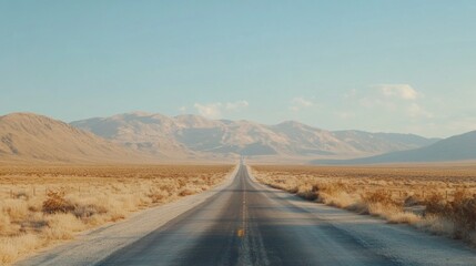 Fototapeta premium A long, straight road stretches through a barren desert landscape, with a mountain range in the distance. The sky is clear and blue, with a few clouds.