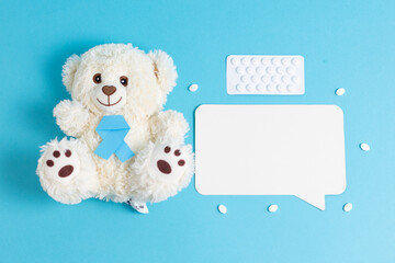 Teddy bear with blue ribbon, pills and empty callout on blue.