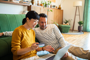 Couple making online payment with credit card and laptop at home
