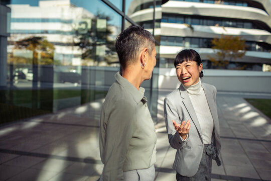 Professional women discussing something on a phone in a modern office building