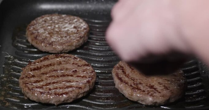 Burger aus saftigem, frischen Rindfleisch werden in einer Grillpfanne gebraten.