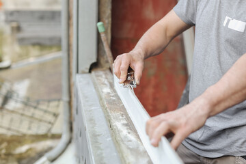 Caucasian male builder clean plastic window with construction knife.