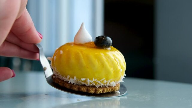 mango cake Eating delicious fresh baked multi-layered mango passionfruit cheesecake slice with fruit jelly glaze on white plate with a spoon close up