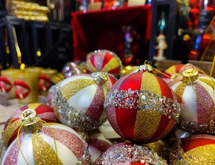 Red gold and white colored Christmas baubles are on a store shelf during a Christmas show in a shop and are ready to be sold before the start of the holiday season