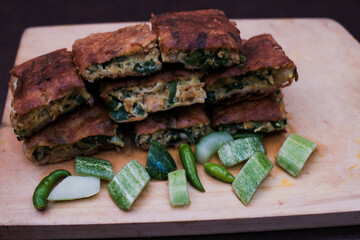 Indonesian Street Food Martabak Telur on the wooden cutting board, with Served pickles, Savory pan-fried pastry stuffed with egg, meat, green onion and spices.