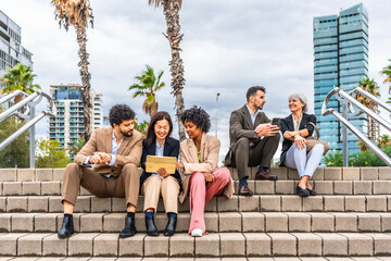 Multi-ethnic business people sitting in the street using digital tablet