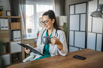 young adult woman doctor read patient file and drink coffee on break