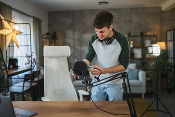 man blogger stand and prepare microphone for new video at home studio