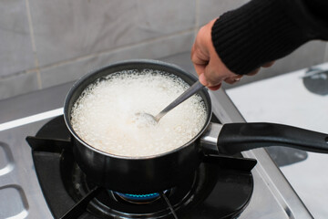 A women cooking the pasta macaroni or penne pasta in wok pan pot in boiling water, cooking pasta homemade.